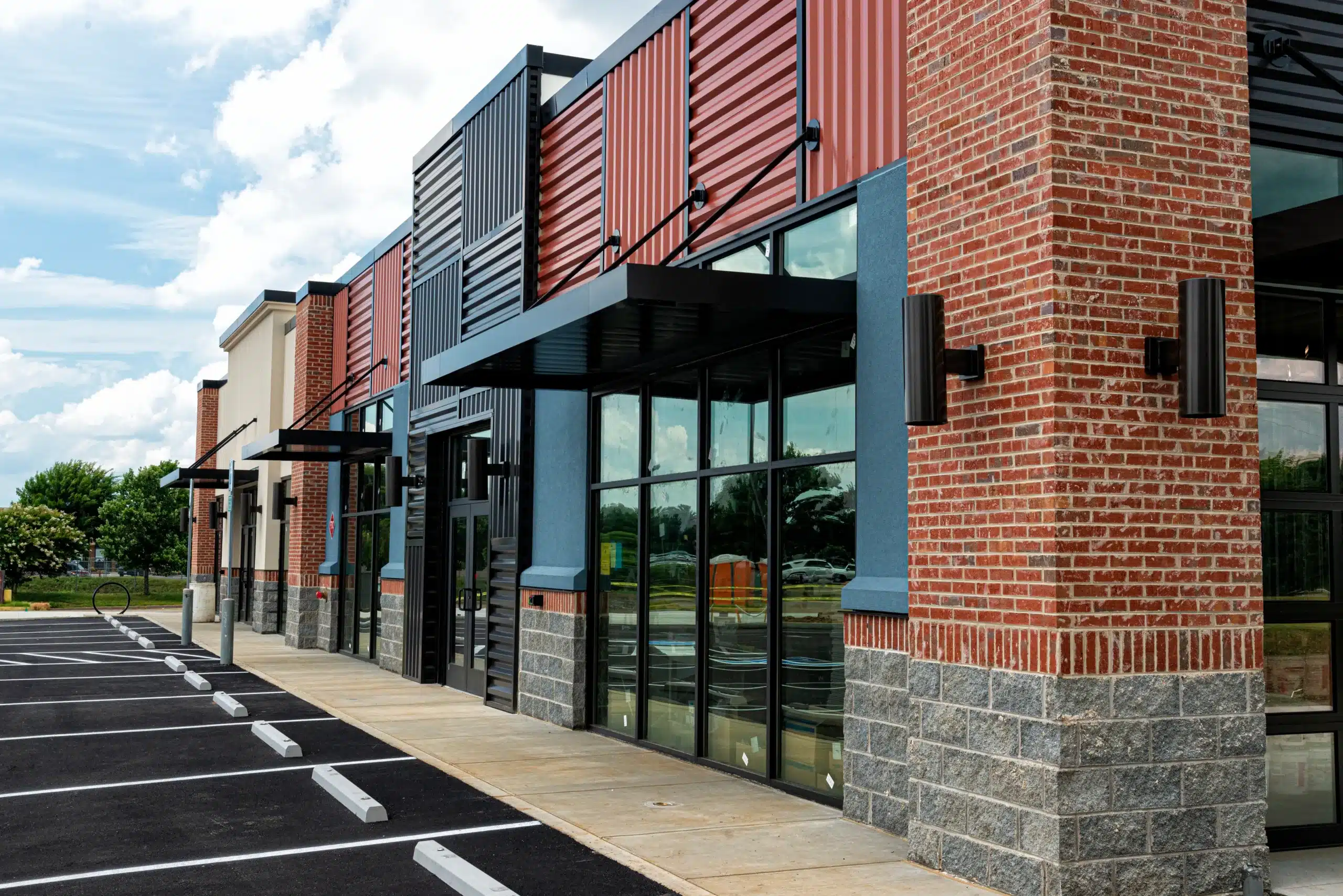 Professional Commercial Exterior Painting Services for Businesses Professional commercial exterior painting on a modern building with red brick, metal siding, and dark grey accents.